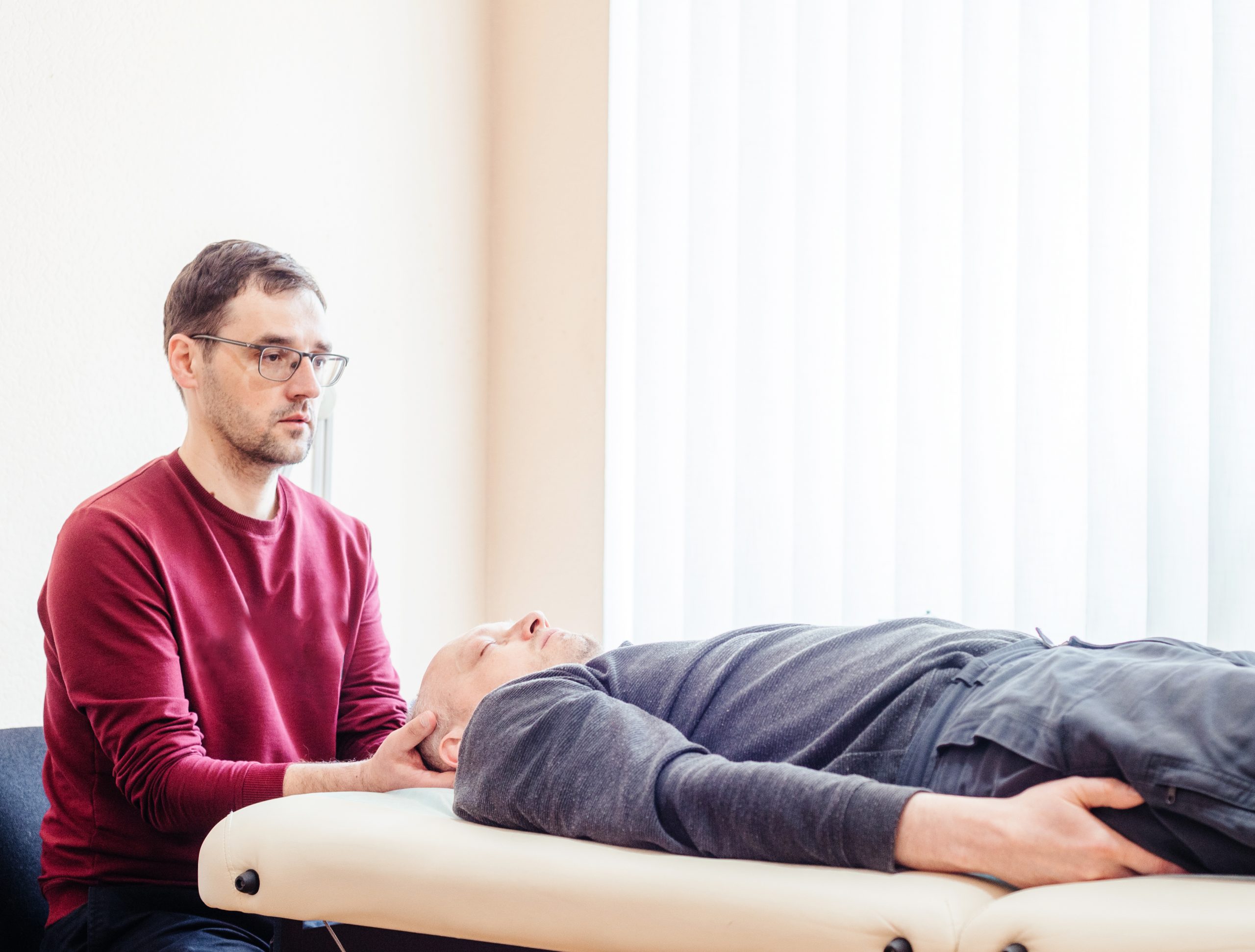 Craniosacral therapy practitioner giving a male patient CST osteopathic treatment